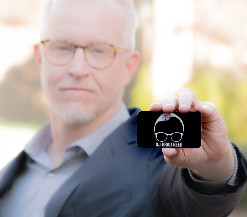 Brad Reed – DJ and owner of 3rd Coast Entertainment, holds a black business card with ""DJ Brad Reed"" and a custom logo.