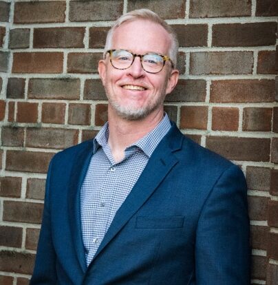 DJ Brad Reed, owner of 3rd Coast Entertainment, wears a navy blue suit.